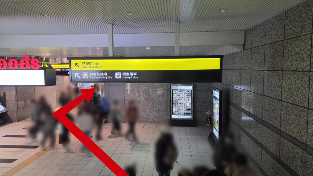 エスカレーターを降りた地下通路の様子。頭上には黄色と黒の案内看板があり、左側にはルクアとの連絡通路があります。