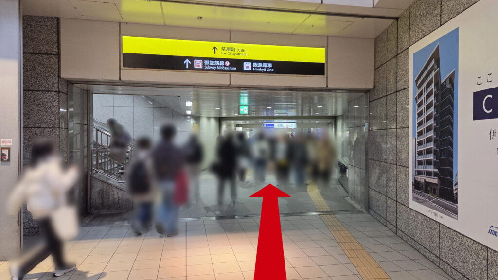 前方に続く地下通路の様子。頭上には「茶屋町方面」「御堂筋線」「阪急電車」と書かれた黄色の案内看板があり、多くの人々が通路を行き交っています。