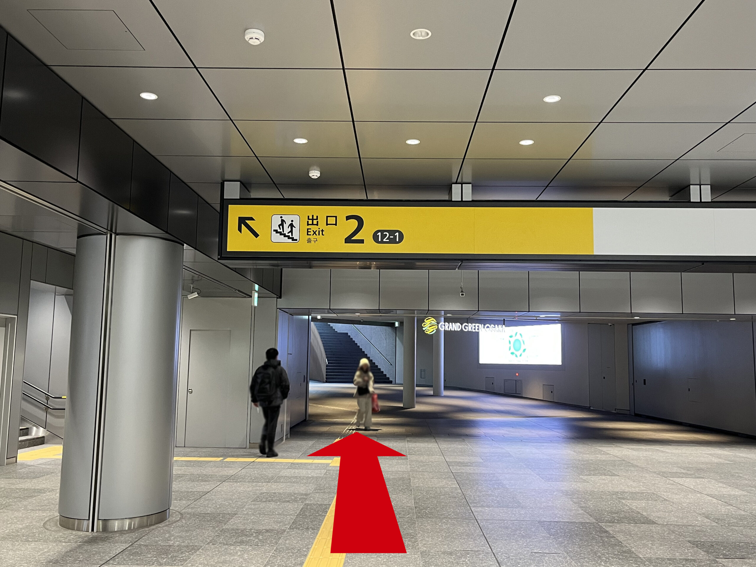 Signature グラングリーン ゲートタワーへのアクセス：出口2の看板の左手に円柱。前方にグラングリーン大阪の看板。矢印が真っ直ぐ伸びている