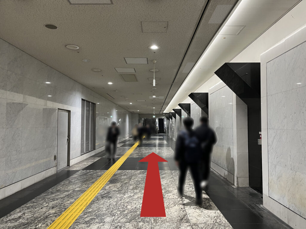 WeWork御堂筋フロンティアへのアクセス:壁際に黒い三角形が並ぶ通路を直進する