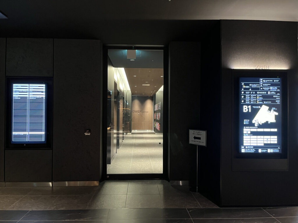 Signature グラングリーン ゲートタワーへのアクセス：「⬅︎ゲートタワー オフィスロビー」と書かれた看板の横に、ゲートタワーオフィスロビーへの入り口がある。左右にはデジタルサイネージ