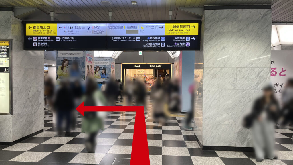 JR大阪駅の御堂筋口改札付近の様子。頭上には御堂筋北口や御堂筋南口、各路線への案内が書かれた黒い大きな看板が設置されており、前方には猪狩スーパーがあります。