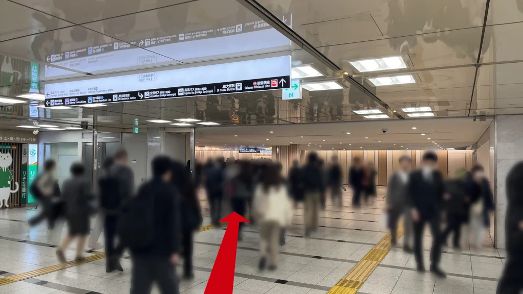 Alt：Signatureグラングリーンゲートタワーへのアクセス方法：多くの歩行者が行き交う地下通路で、左側の壁面に「りそな銀行」の緑色のサインとキャラクターイラストが表示されている様子。