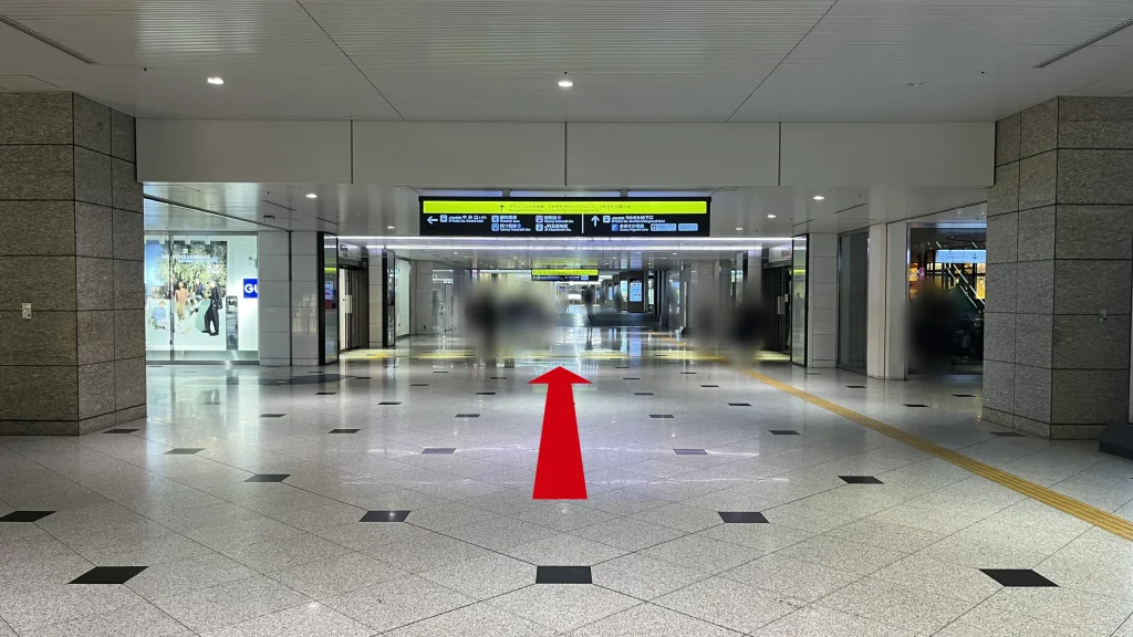 Signature グラングリーン ゲートタワーへのアクセス方法：左側に「GU」の店舗がある非常に道幅の広い地下通路を直進する様子。天井からは「グランフロント大阪」方面を示す黄色と黒の看板が吊り下げられている。