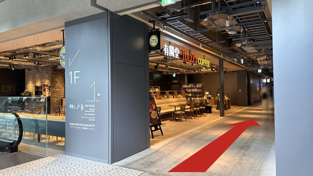 JAM BASEへのアクセス：グラングリーン大阪北館の館内に入り、タリーズコーヒーの前の通路を進む矢印の図