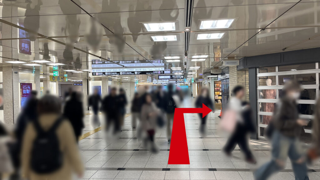 ワークスタイリング梅田へのアクセス：通路が交差する地下空間で、店舗沿いに道なりに進む