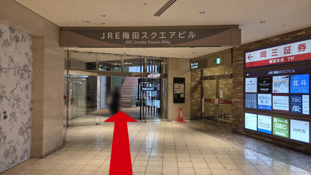 リージャス梅田スクエアビジネスセンターへのアクセス方法：「JRE梅田スクエアビル」の地下連絡通路　右に「岡三証券」のテナント看板と外へつながる「E-2」出口が見える