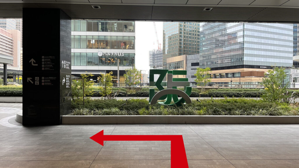 Compass Offices イノゲート大阪へのアクセス：ルクアイーレを突っ切って外に出た図　正面に「阪」のモニュメント、左手の大きな柱に案内が書かれている　左手奥に「バルチカ03」と書かれたイノゲート大阪のビルが見える