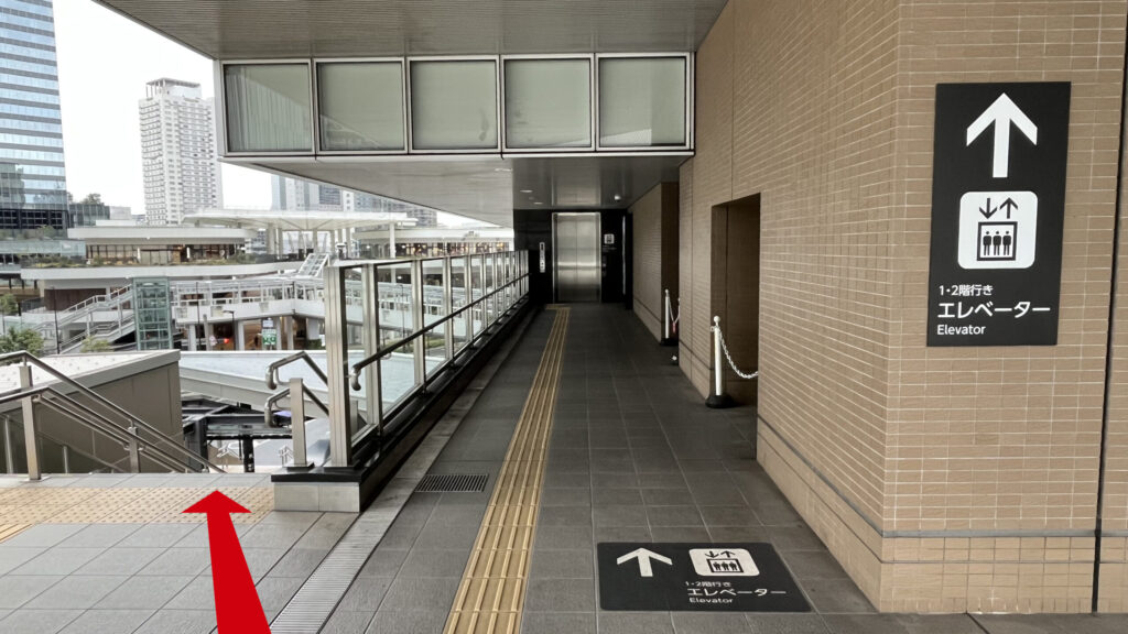 Compass Offices イノゲート大阪へのアクセス：1・2階行きエレベーターと書かれた、エレベーターへ通じる通路と、その左には下りの階段がある