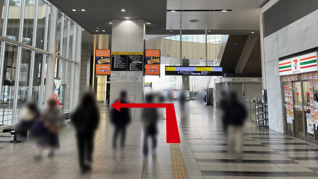 Compass Offices イノゲート大阪へのアクセス：右手にセブンイレブン、左手にガラス張りの窓がある　正面には大きな柱に案内掲示が貼られており、正面右にはインフォメーション、正面奥には案内板が吊り下げられている