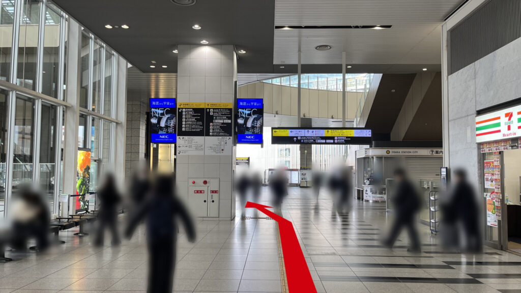 SHARE LOUNGE梅田 蔦屋書店へのアクセス：JR大阪駅連絡橋口を出て右手に直進した図　右側にセブンイレブン、左側に大きいガラス張りの窓、左前方に案内が貼られた大きな四角の柱、右前方にインフォメーションがある