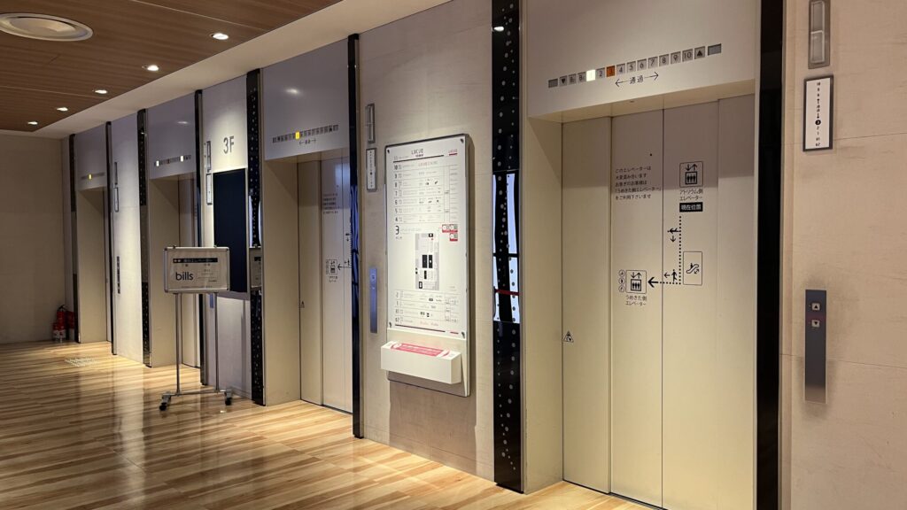 SHARE LOUNGE梅田 蔦屋書店へのアクセス：一つ前の写真奥に写っていたエレベーターホール　白いエレベーターが4機並んでいる