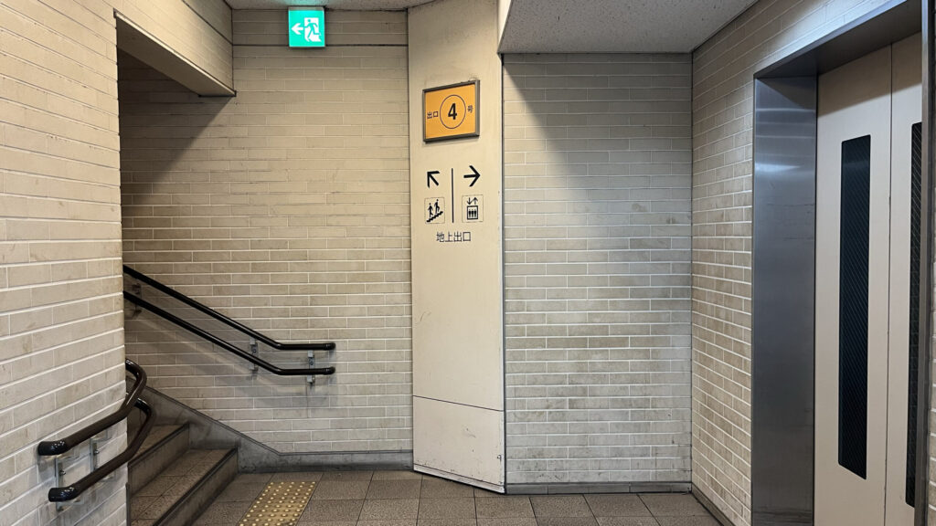 BIZcomfort大阪東梅田へのアクセス方法：地下から地上へ続く「4番出口」の階段とエレベーターのピクトグラム案内　右手にエレベーター、左手に上へ上る階段