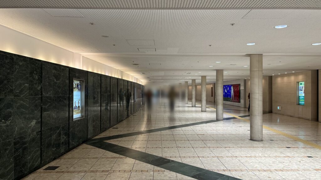 リージャスパシフィックマークス西梅田ビジネスセンターへのアクセス方法：等間隔に白い円柱が配置された地下通路　左手に大理石のような石の壁が連なっている