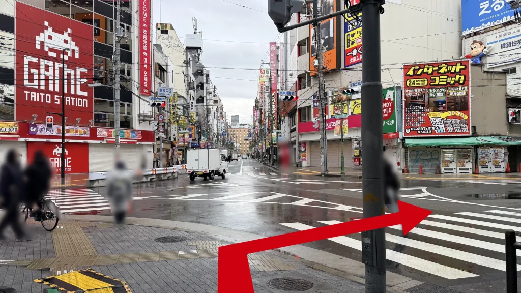 TAITO STATIONの赤い看板とインターネットコミックと書かれた看赤い板が見える交差点の写真