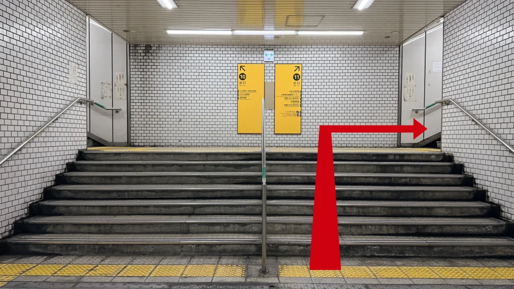 10番出口と11番出口に分かれる階段の正面。右側の11番出口を指す赤い矢印。