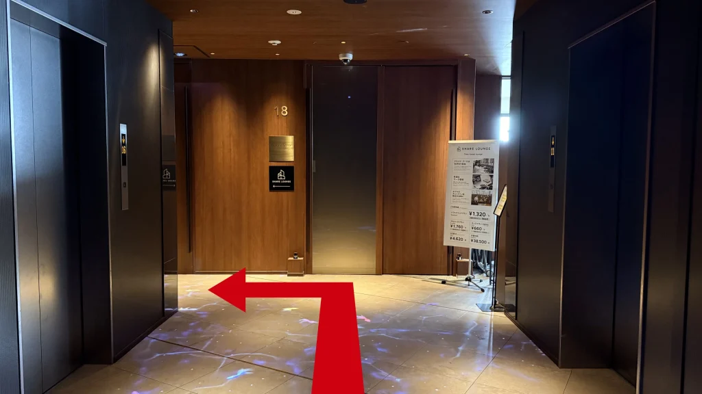 18Fエレベーターホール。左側に受付があることを示す矢印。