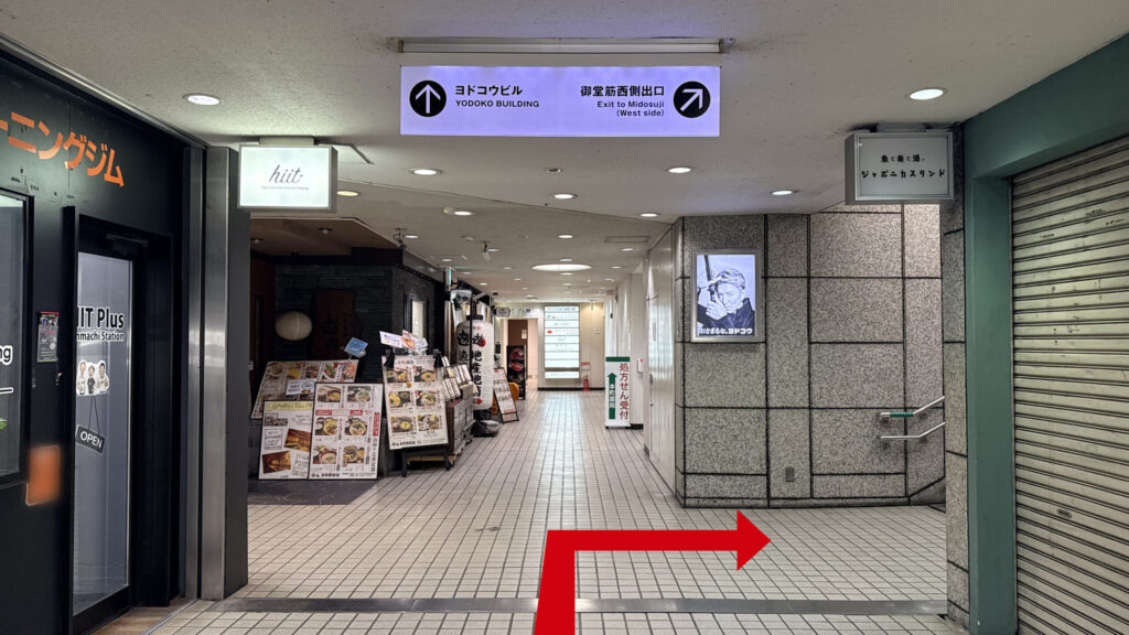 H¹O 本町Ⅱへの行き方:飲食店などが並ぶ地下通路の風景。頭上の看板に「ヨドコウビル 御堂筋西側出口」とあり、右奥に地上へ続く階段が見える。