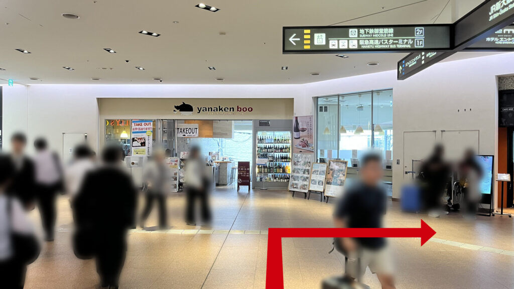 リージャス新大阪阪急ビルビジネスセンターへの行き方:通路の突き当たりにある飲食店の外観と、頭上に設置された「地下鉄御堂筋線」や「高速バスターミナル」へ誘導する黒い案内看板。