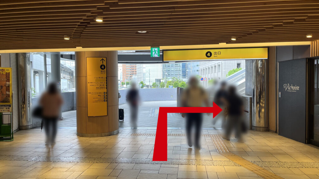4番出口と書かれた黄色い案内看板の下を通り、屋外の開けたスペースへと向かう通路の様子。