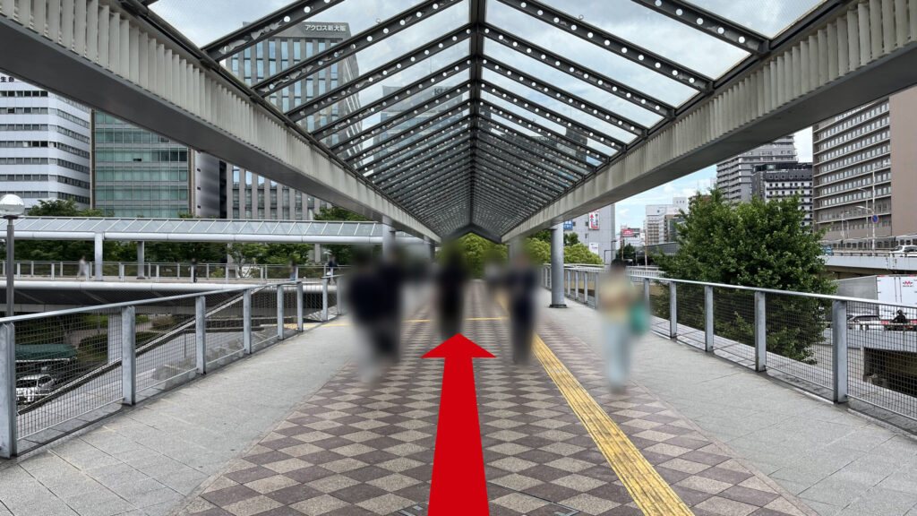ガラス張りのアーチ状の屋根が設置された、タイル敷きのペデストリアンデッキを直進する通路の様子。