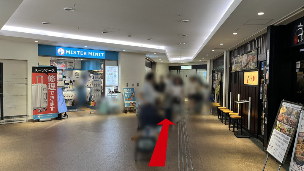 エスカレーターを下に降りて見える図 右には飲食店、左には靴などの修理屋さんがある