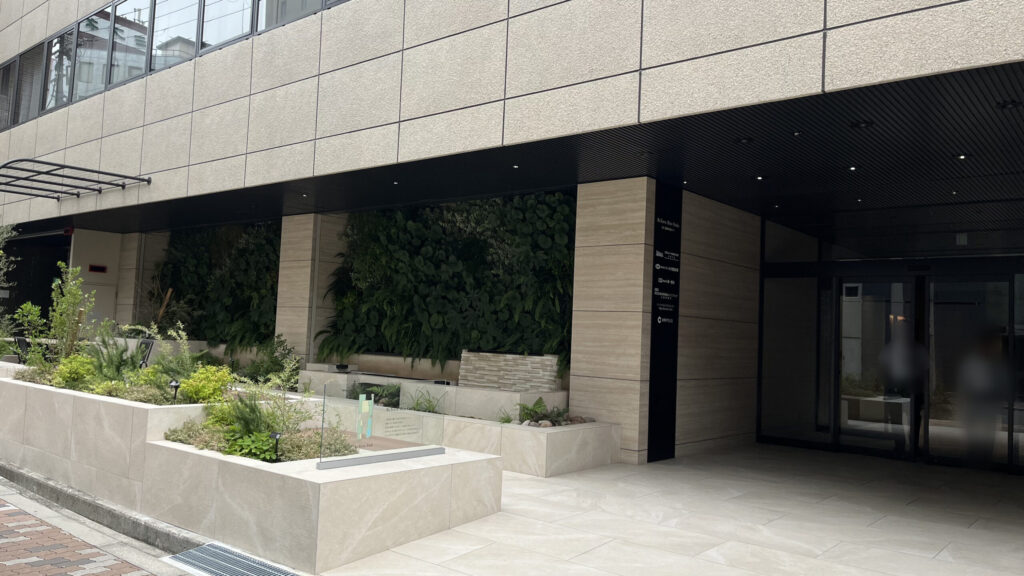 「ReTerra新大阪」外観　黄土色のタイル調で、右側にエントランスがある　建物の前には観葉植物が植えられている