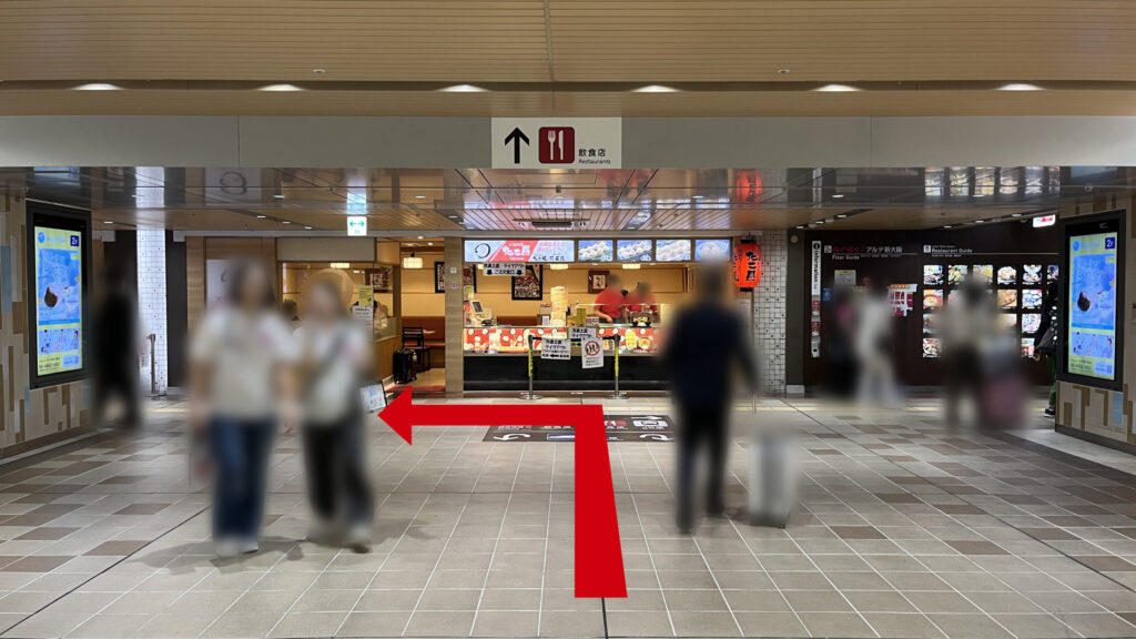 正面に「たこ昌」がある通路の風景　頭上に「↑飲食店」と書かれた掲示板がある
