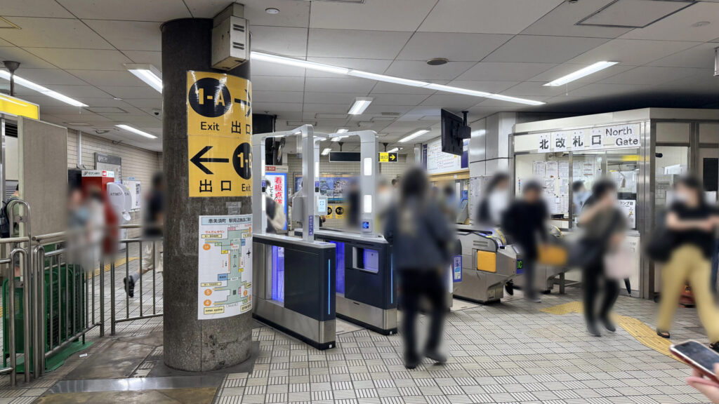 地下鉄堺筋線恵美須町駅の北改札口を出た正面の景色。改札口の横に「北改札口 North Gate」と書かれた駅務室があり、左側の柱には「出口 1-A 1-B」の案内看板が設置されている。