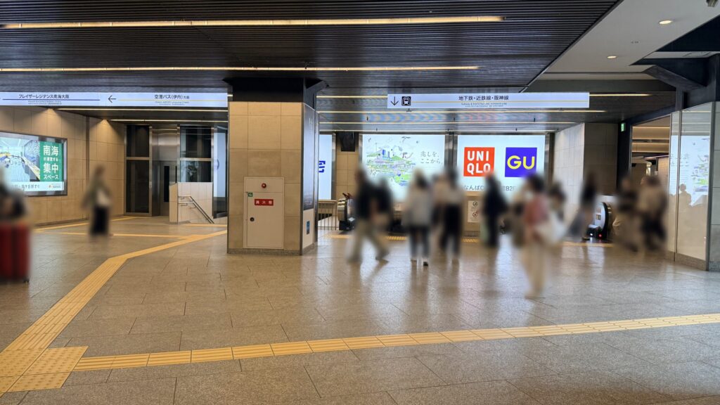 正面に大きな広告ボードが掲げられたコンコース。上部には「地下鉄・近鉄・阪神線」への案内看板が設置されている。