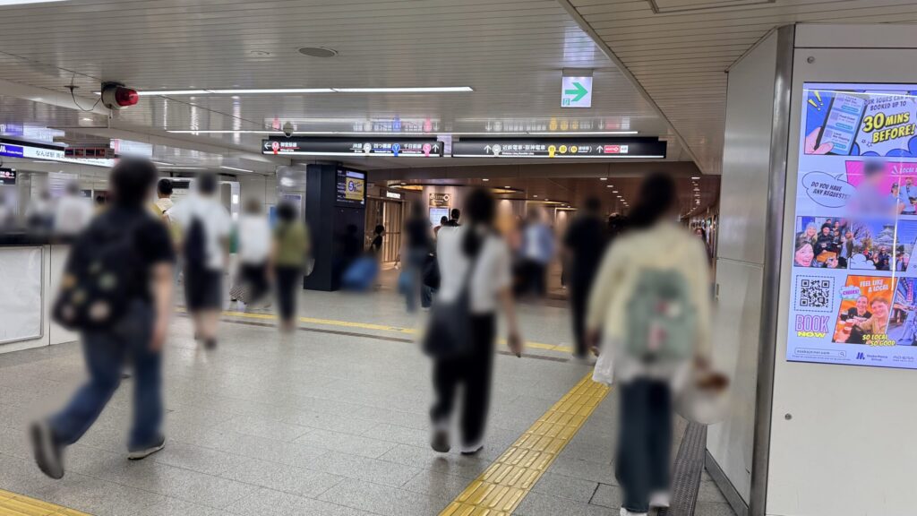 頭上に御堂筋線や四つ橋線などの路線案内看板が吊り下げられた地下通路。奥に向かって一直線に道が伸びている様子。