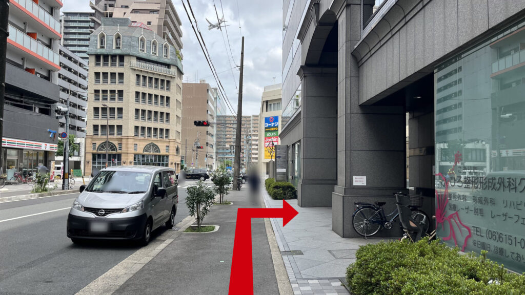 目的地付近 正面に交差点とコーナンなどの商業施設の看板、車道を挟んで左側にセブンイレブンがある