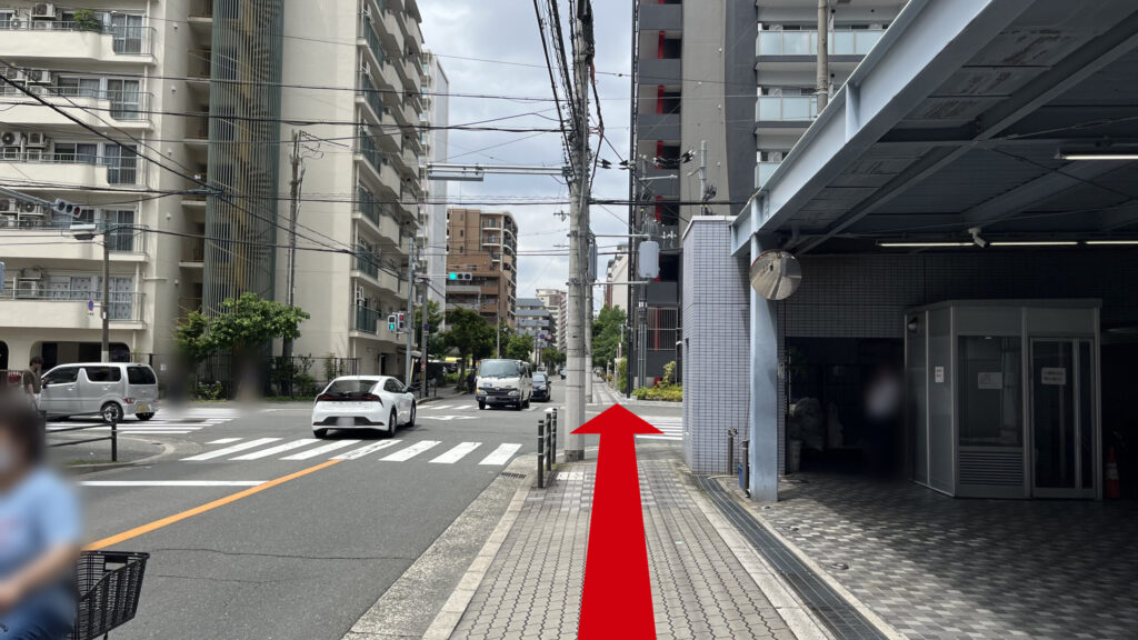 右側にビル1Fにある駐車場、歩道の先、正面にマンションが連なっている 左には車道がある