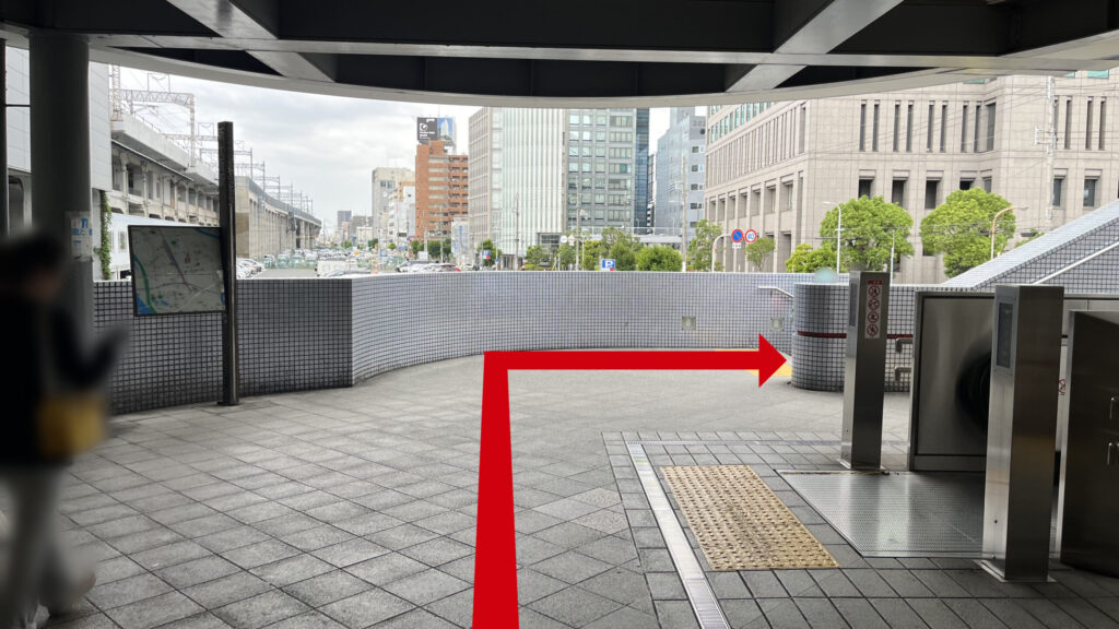 4番出口と書かれた黄色い案内看板の下を通り、屋外の開けたスペースへと向かう通路の様子。