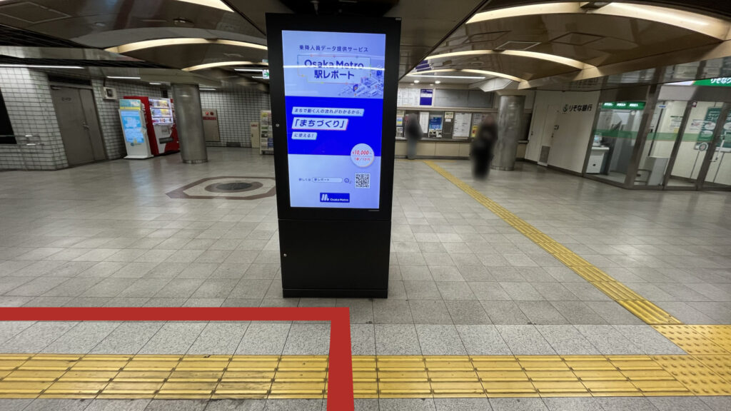 御堂筋線北北改札を出た時に見える風景 正面にデジタルサイネージ、その奥にりそな銀行ATMときっぷ券売機、自販機などが並んでいる
