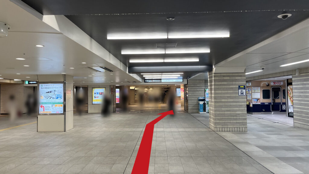阪神大阪梅田駅の百貨店口改札を出て右に曲がった時に見える風景 右奥に宝くじ売り場、正面にディアモールへ通じている通路、通路両脇に等間隔に四角の柱が並んでいる