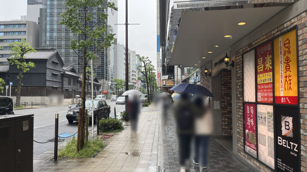6号出口から地上に出て右に向いた風景 鳥貴族などの飲食店の看板が建物に掲示されており、左に堺筋が通っている